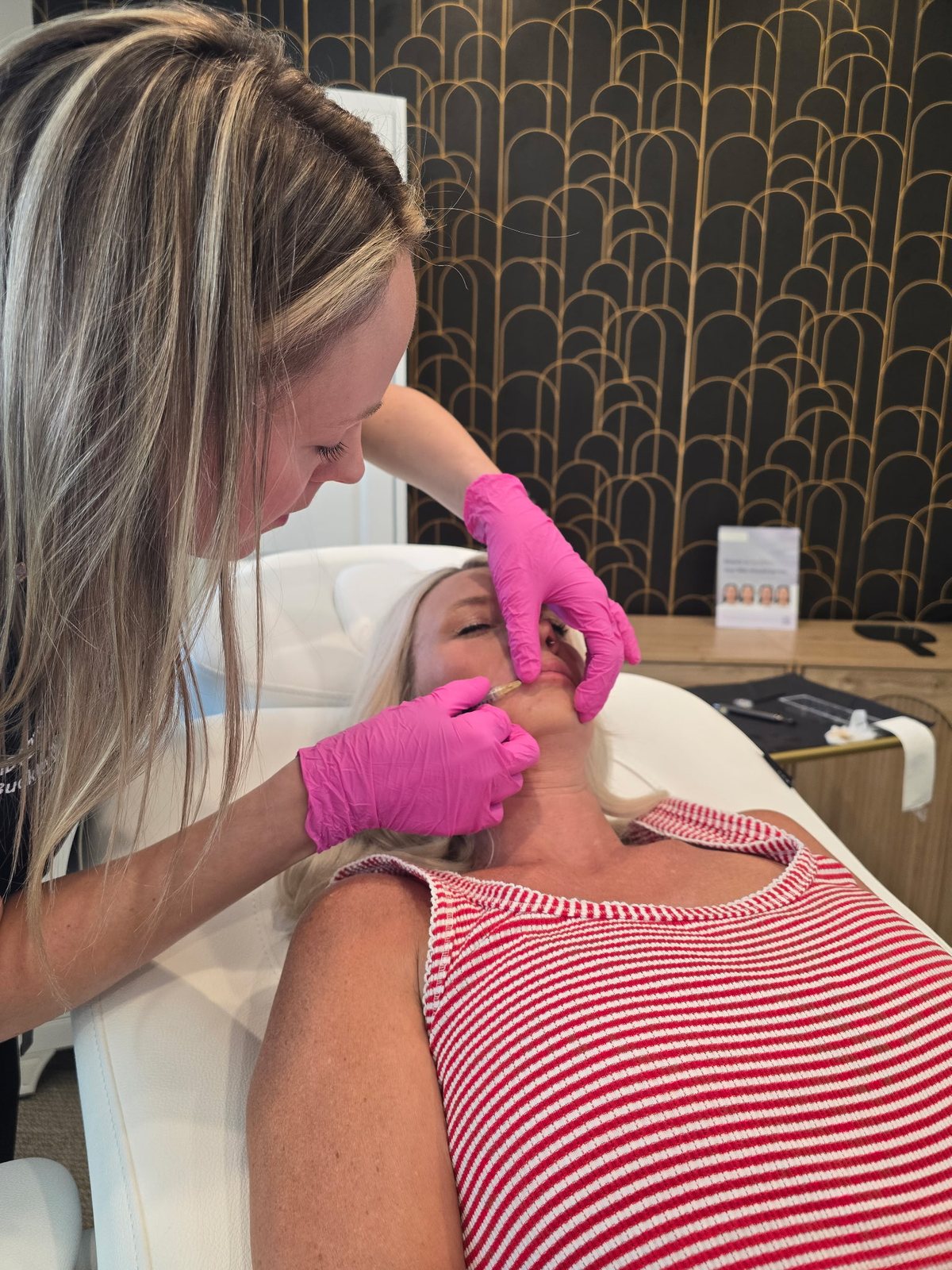 Sara Buckley performing lip filler in the gold art-deco treatment suite